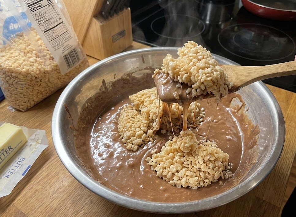 Mixing Rice Krispies into gooey melted mixture